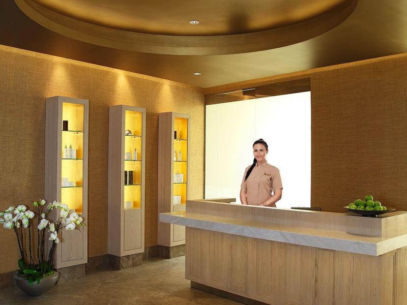 Nowoczesna recepcja z ladą i ciepłym oświetleniem, ozdobiona roślinami i kwiatami.