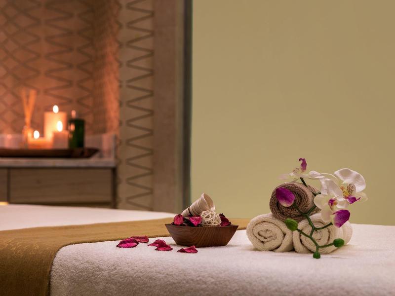 Przytulne spa z pachnącymi świecami, ręcznikami i orchideami na stole do masażu.