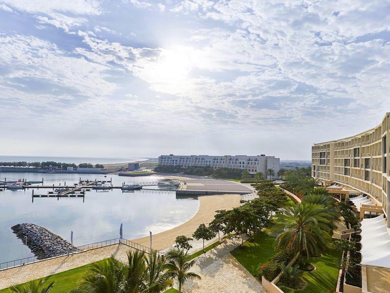 Plaża z mariną i balkonami hotelowymi pod pochmurnym niebem.