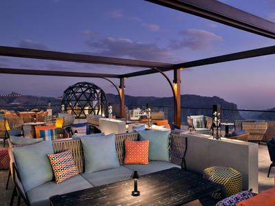 Gemütliche Dachterrasse mit Sofas, Tischen und Laternen bei Sonnenuntergang mit Bergblick.