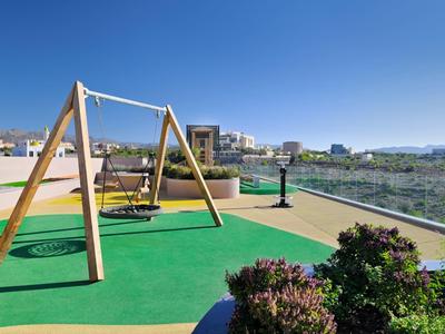 Houpačka na střešní terase s výhledem na město a hory za jasné oblohy.