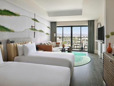 Moderní hotelový pokoj se dvěma jednolůžky, balkonem a panoramatickým výhledem na město.