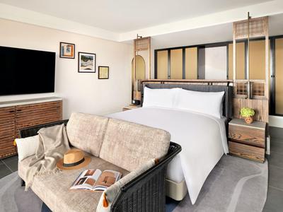 Moderní hotelový pokoj s velkou postelí, pohodlnou pohovkou a plochou televizí.