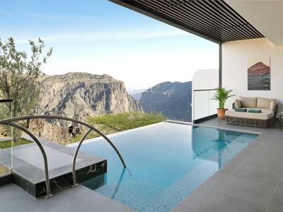 Infinity bazén s výhledem na hory a moderní venkovní posezení.