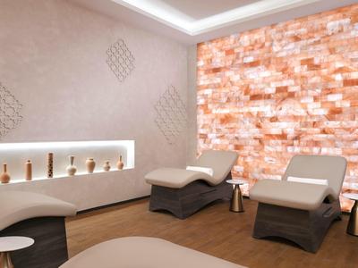 Moderní spa s pohodlnými lehátky a teplým osvětlením na stěně ze solného kamene.