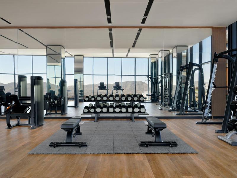 Moderní posilovna s činkami, lavičkami a velkými okny s výhledem na město