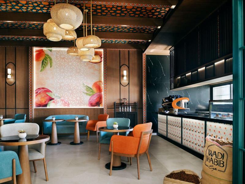 Příjemná hotelová restaurace s moderními židlemi a uměleckou nástěnnou malbou.