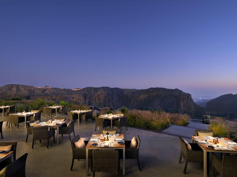 Venkovní restaurace s výhledem na horskou krajinu při západu slunce.