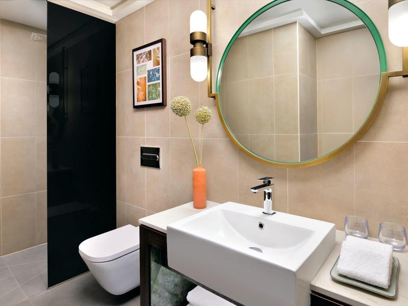 Moderní koupelna se zrcadlem, umyvadlem a závěsným záchodem v neutrálních tónech.