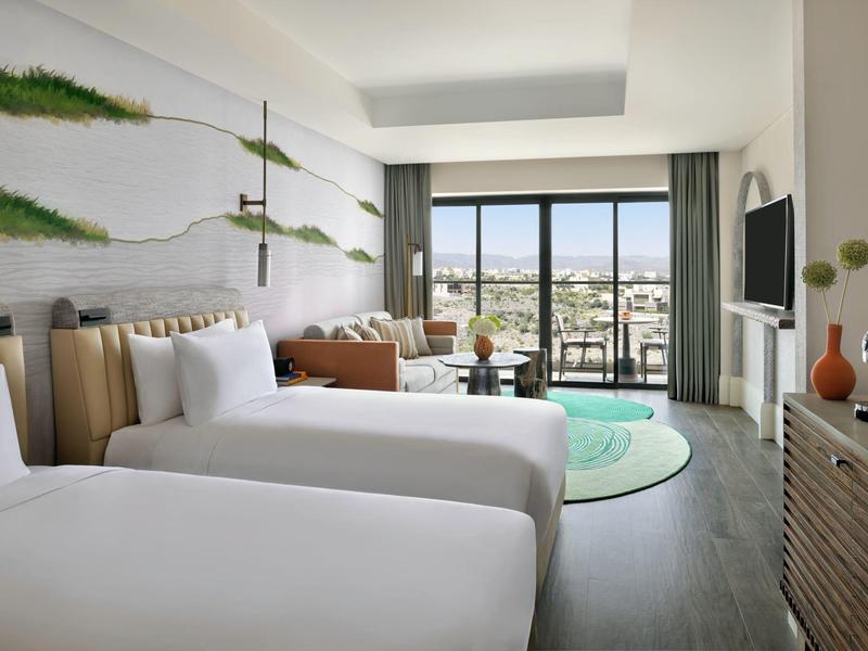 Moderní hotelový pokoj se dvěma jednolůžky, balkonem a panoramatickým výhledem na město.