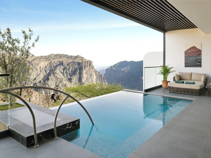 Infinity bazén s výhledem na hory a moderní venkovní posezení.