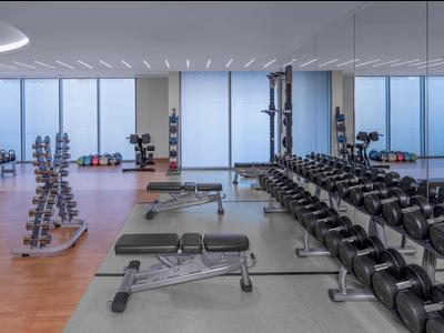 Moderne Fitnessstudio mit Hanteln, Bänken und großem Fenster mit Blick nach draußen.
