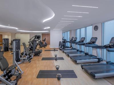 Moderner Fitnessraum mit Laufbändern, Fahrradergometern und Gewichten in einem Hotel.