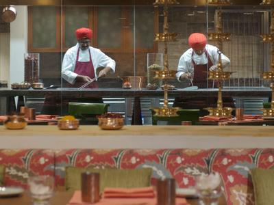 Twee koks met rode hoeden werken in een open keuken van een restaurant.