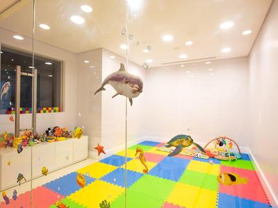 Kleurrijke speelkamer met zachte vloer, speelgoed en een hangende haai decoratie.