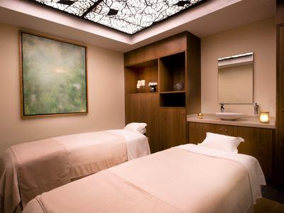 Kamer met twee massagetafels, warm verlicht en met rustgevende inrichting.