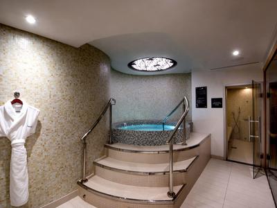 Luxe bubbelbadruimte met trappen, leuningen en een badjas aan de muur