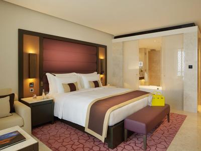 Habitación de hotel moderna con cama grande, zona de estar y acceso al baño.