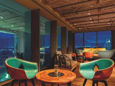 Modern eingerichteter Hotel-Lounge-Bereich mit Holzdecke und bodentiefen Fenstern bei Nacht.