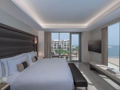 Moderne hotelkamer met groot bed, panoramische ramen en uitzicht op zee.