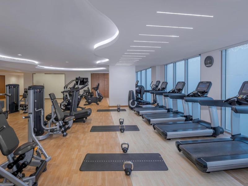 Moderne sportschool met loopbanden, krachtapparaten en dumbbells in een lichte ruimte.