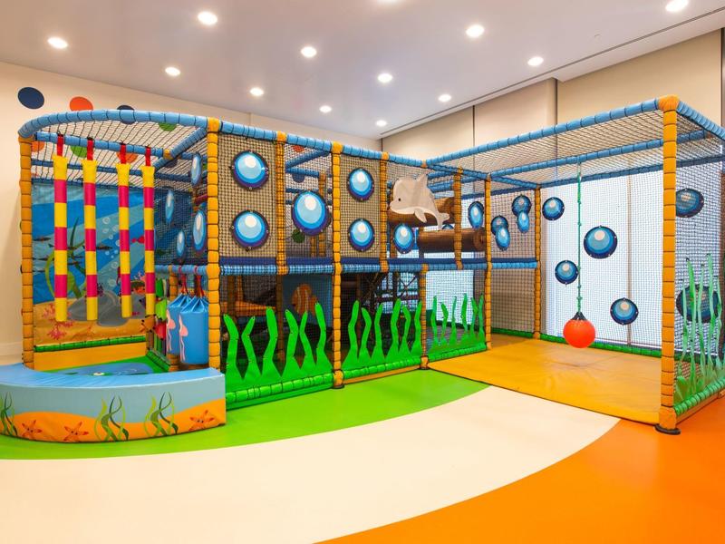 Overdekte speelruimte met klimrek, glijbanen en zachte speelballen in een hotel voor kinderen.