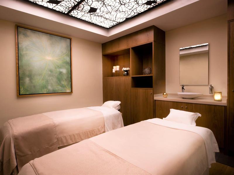 Kamer met twee massagetafels, warm verlicht en met rustgevende inrichting.