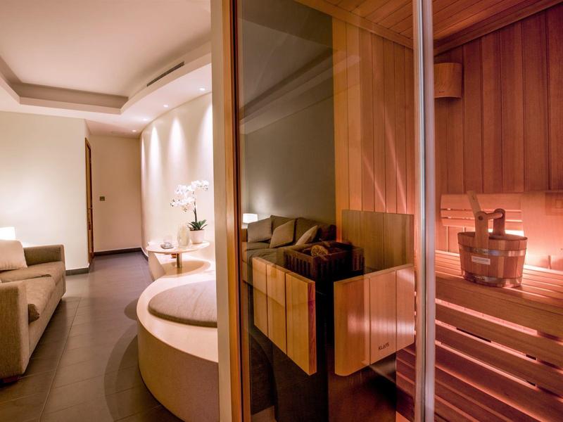 Moderne sauna met glazen deur, zitplaatsen en gedimd licht.