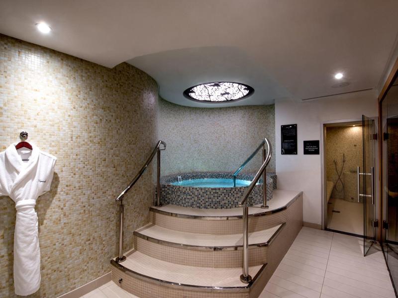 Luxe bubbelbadruimte met trappen, leuningen en een badjas aan de muur