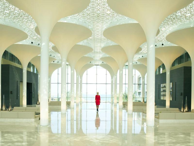 Lichte lobby met wit zuilenontwerp en een persoon in rode outfit centraal staand