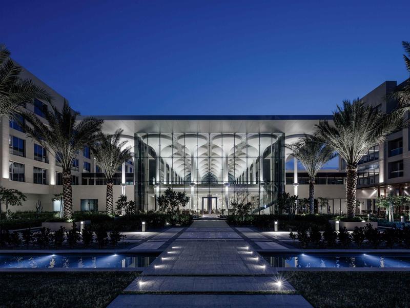 Modern hotel 's nachts met verlichte ingang en palmbomen