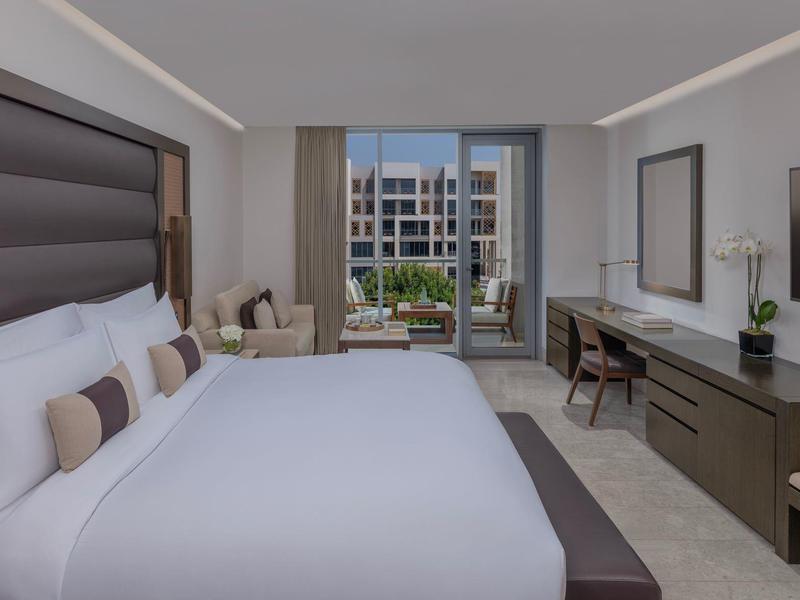 Moderne hotelkamer met groot bed, bureau en uitzicht op het zwembadgebied.