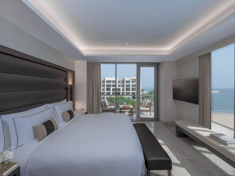 Moderne hotelkamer met groot bed, panoramische ramen en uitzicht op zee.