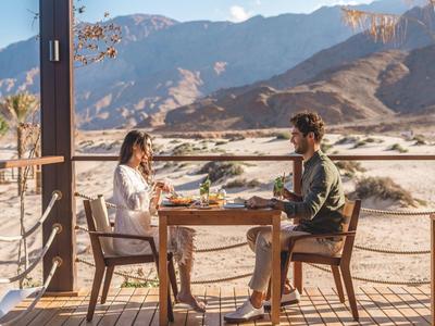 Couple sitting at a table on a terrace with mountain view in sunny weather.