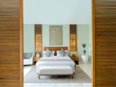 Modern hotel room with large bed, wooden walls, and minimalist decoration.