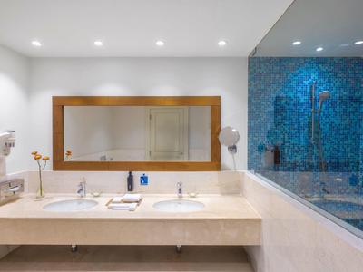 Modern bathroom with double sinks and blue mosaic shower wall.