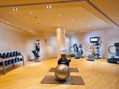 Moderner Fitnessraum mit Hanteln, Gymnastikbällen und Trainingsgeräten in hellem Raum.