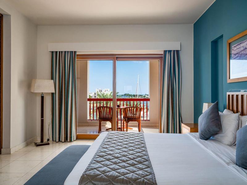 Modern hotel room with a large bed, balcony, and sea view.