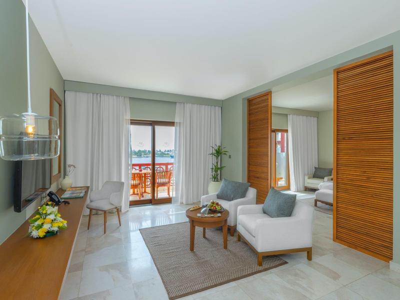 Bright living room with sofa, table, chairs, and balcony access with sea view.