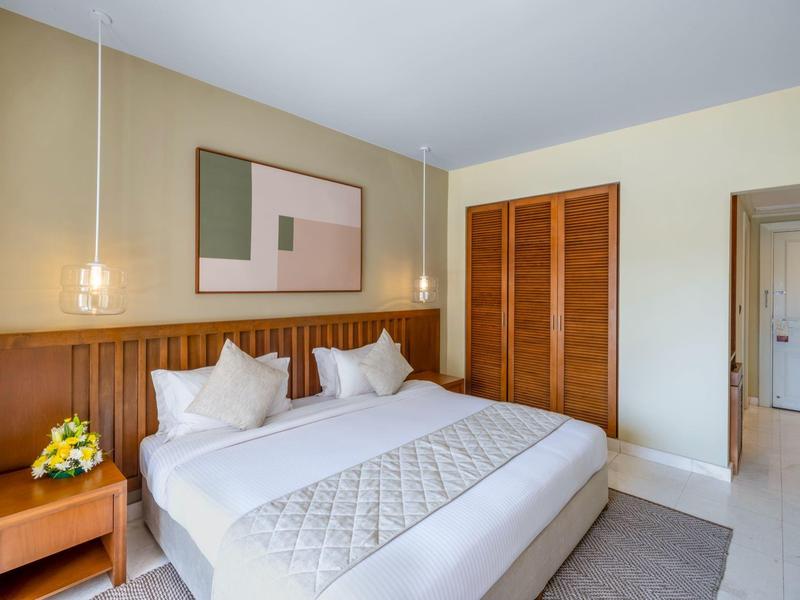 Cozy hotel room with double bed, nightstand, flowers, and modern wall decoration.