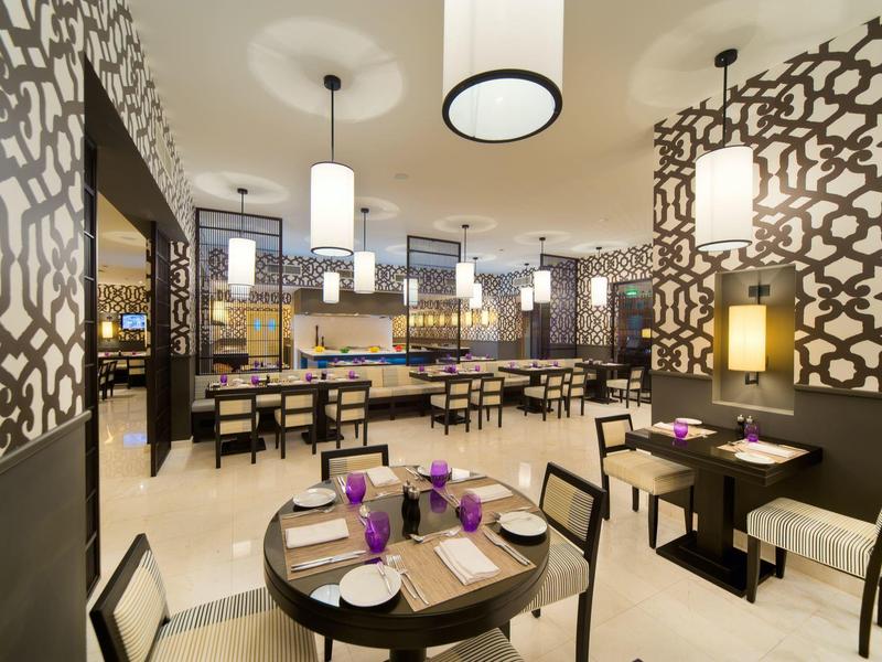 Modern restaurant with geometric wall decor and set tables with flowers.