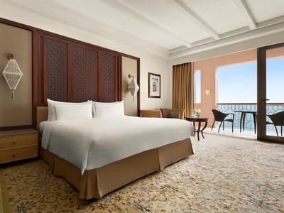 Prostorný hotelový pokoj s manželskou postelí a balkonem s výhledem na moře.