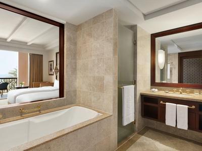 Moderní koupelna s vanou, velkým zrcadlem a umyvadlem v světlých béžových tónech.