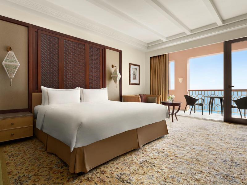 Prostorný hotelový pokoj s manželskou postelí a balkonem s výhledem na moře.