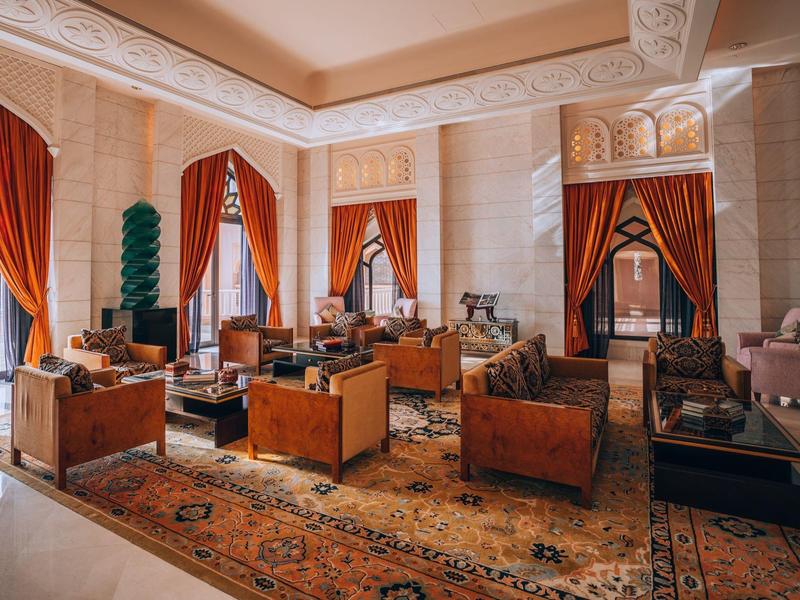 Elegantní hotelový salón s oranžovými závěsy a klasickým nábytkem.