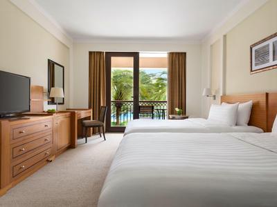 Chambre d'hôtel avec deux lits, balcon et vue sur des palmiers.