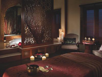 Salle de spa confortable avec table de massage, bougies et ambiance relaxante.
