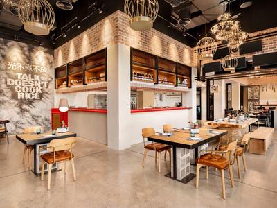 Restaurant moderne et lumineux avec des chaises en bois, des tables et un éclairage industriel.