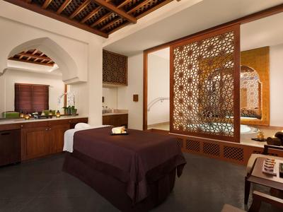Salle de spa élégante avec table de soin, plafond en bois et écran décoratif.