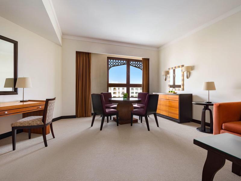 Chambre d'hôtel moderne avec bureau, coin salon et balcon avec vue sur la montagne.